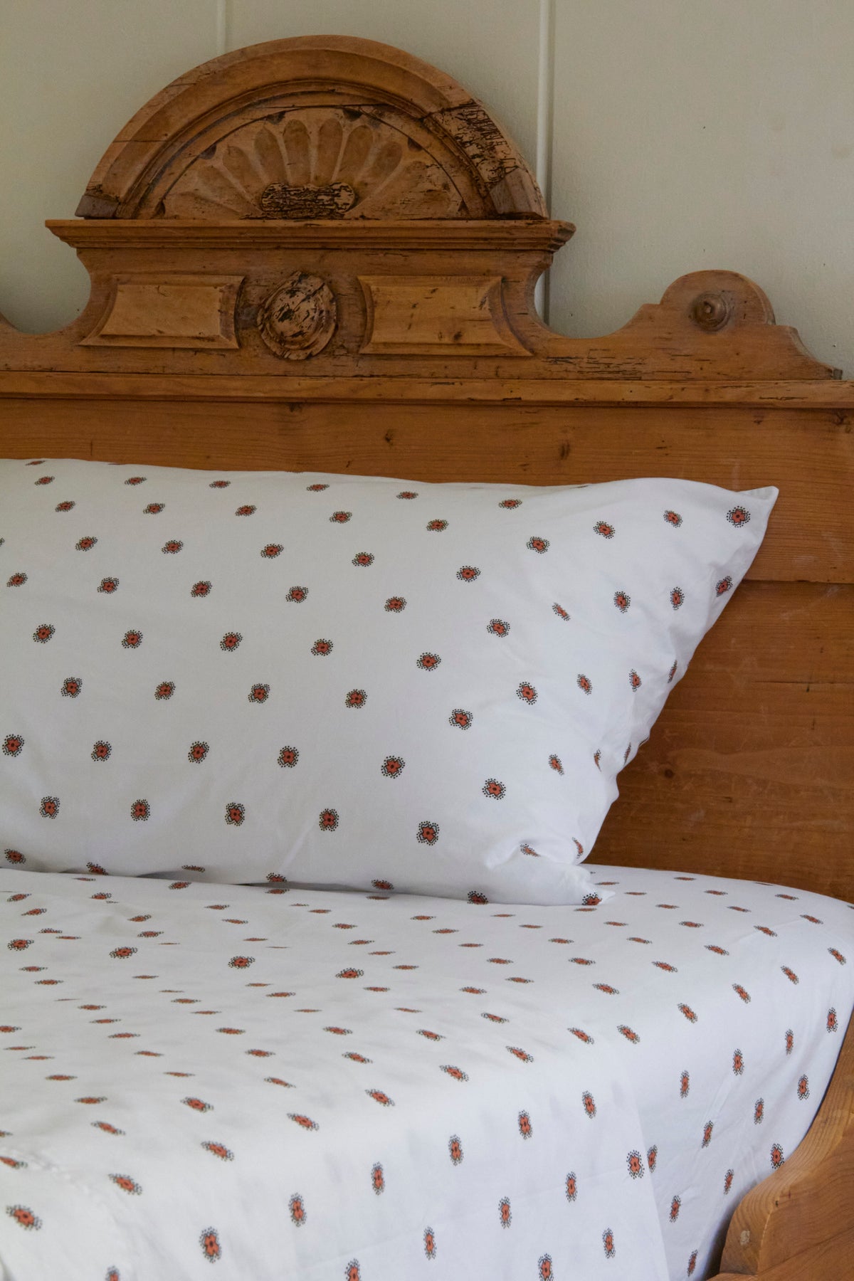 Wooden headboard with white pillow and sheet, floral pattern.