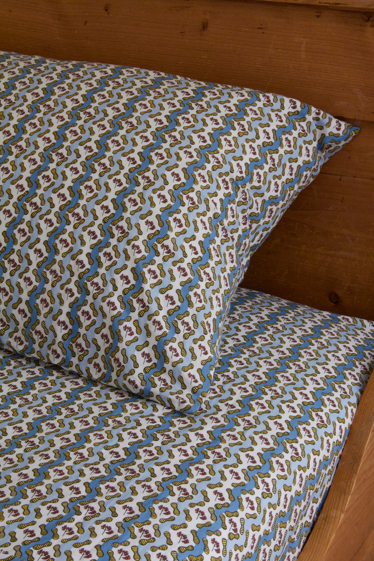Colorful snake-patterned pillow and sheet on a wooden bed.