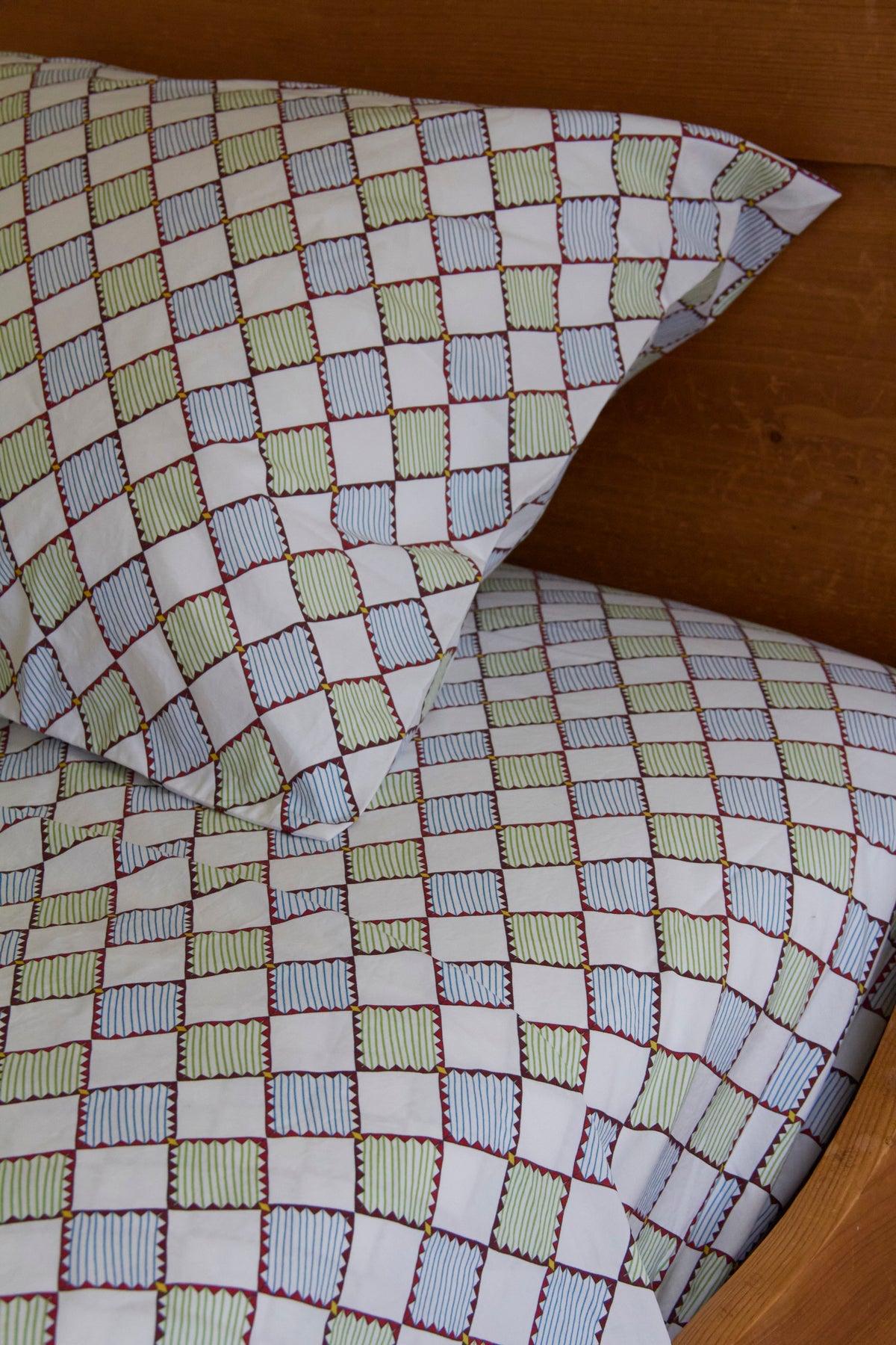 Checkered bed sheet and pillow with green, blue, and white squares.