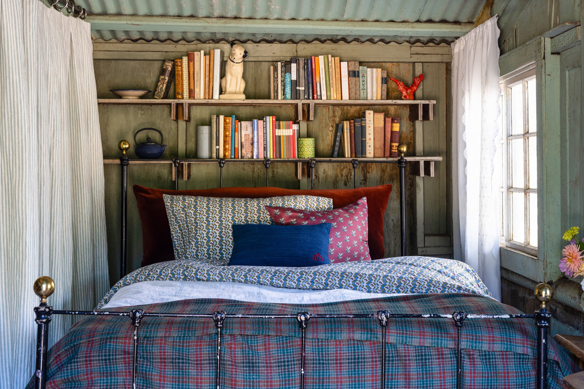 Cozy bedroom with a metal bed, colorful pillows, and bookshelves.