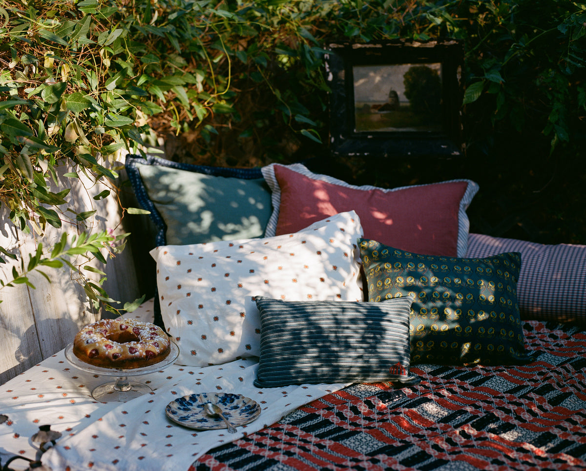 Outdoor garden seating with decorative cushions, patterned blankets and a cake on a table