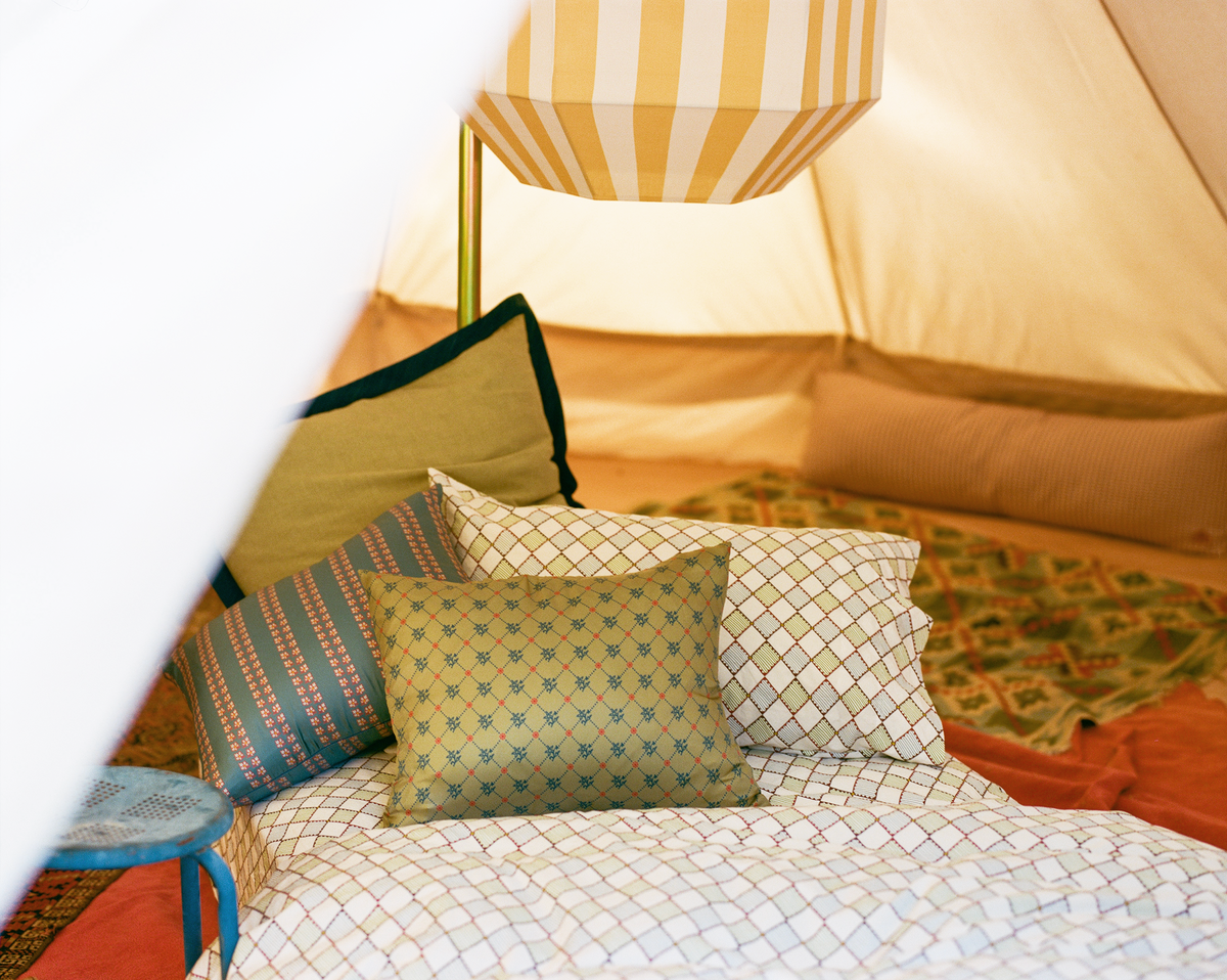 Cozy tent interior with patterned pillows and bedding.